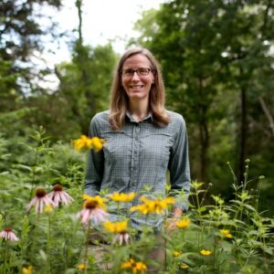 Photo of a woman behind a variety of flowering plants.